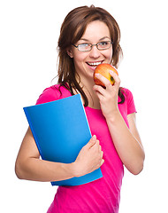 Image showing Young student girl is holding book and apple