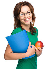 Image showing Young student girl is holding book and apple