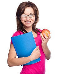 Image showing Young student girl is holding book and apple