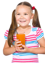 Image showing Little girl is drinking carrot juice