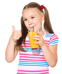 Image showing Little girl is drinking orange juice