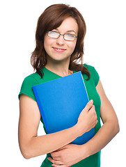 Image showing Young skinny student girl is holding exercise book