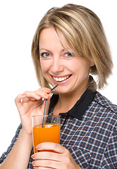 Image showing Young woman is drinking carrot juice