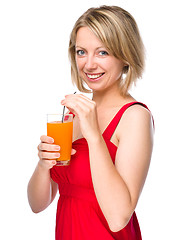 Image showing Young woman is drinking carrot juice