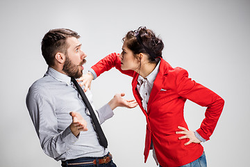 Image showing The angry business man and woman conflicting on a gray background