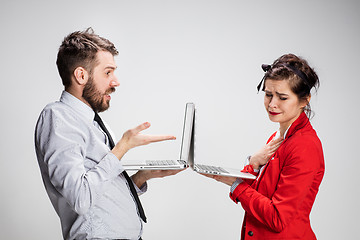 Image showing The young businessman and businesswoman with laptops communicating on gray background