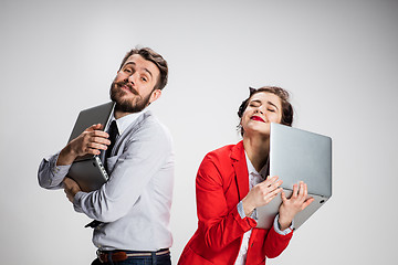 Image showing The young businessman and businesswoman with laptops on gray background