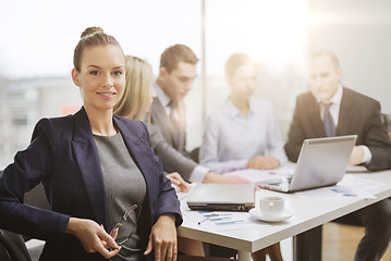 Image showing businesswoman with glasses with team on the back