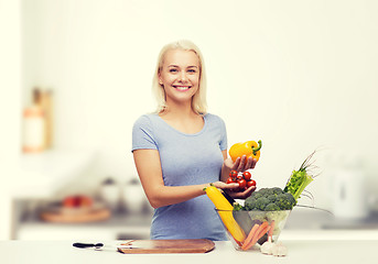 Image showing smiling young woman cooking vegetables in kitchen 