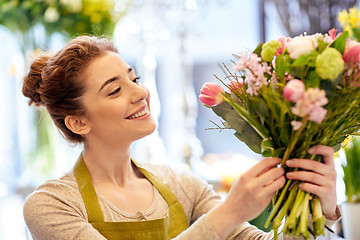 Image showing smiling florist woman making bunch at flower shop