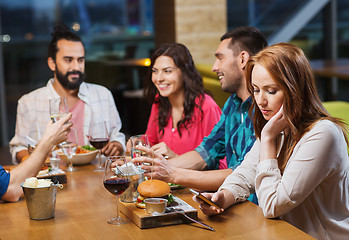 Image showing woman with smartphone and friends at restaurant
