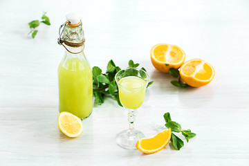 Image showing Home orange liquor in a glass and fresh oranges on the white wooden background