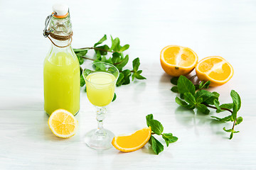 Image showing Home orange liquor in a glass and fresh oranges on the white wooden background