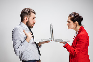 Image showing The young businessman and businesswoman with laptops communicating on gray background