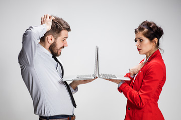 Image showing The young businessman and businesswoman with laptops communicating on gray background