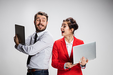 Image showing The young businessman and businesswoman with laptops communicating on gray background