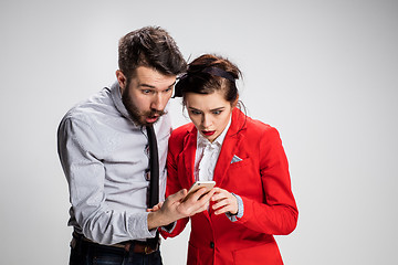 Image showing Business concept. The two young colleagues holding mobile phone on gray background