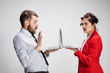 Image showing The young businessman and businesswoman with laptops communicating on gray background