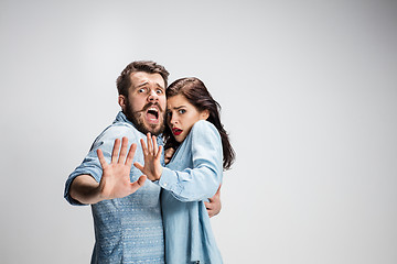 Image showing Close up Shocked Young Couple with Mouth and Eyes Wide Open Looking at Camera on gray Background.