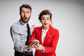 Image showing Business concept. The two young colleagues holding mobile phone on gray background