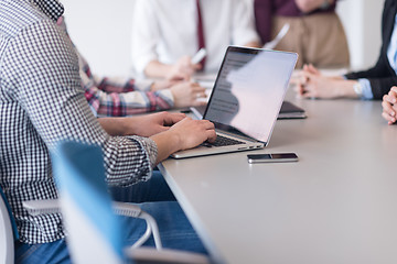 Image showing close up of business man hands typing on laptop with team on mee