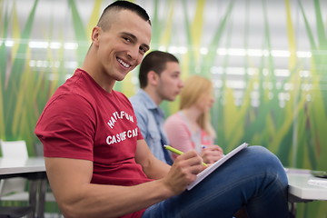 Image showing male student taking notes in classroom