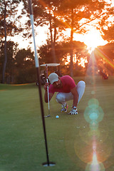 Image showing golf player aiming perfect  shot on beautiful sunset