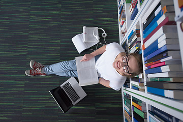 Image showing female student study in library, using tablet and searching for 