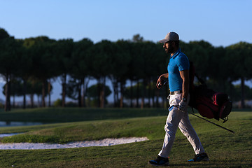 Image showing golfer  walking and carrying golf  bag at beautiful sunset