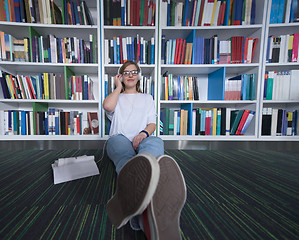 Image showing female student study in library, using tablet and searching for 