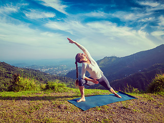 Image showing Woman practices yoga asana Utthita Parsvakonasana outdoors