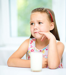 Image showing Sad little girl with a glass of milk