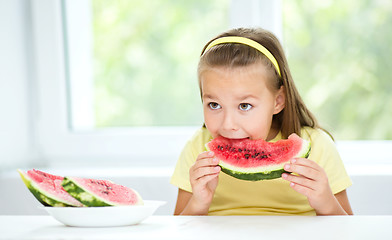 Image showing Cute little girl is eating watermelon