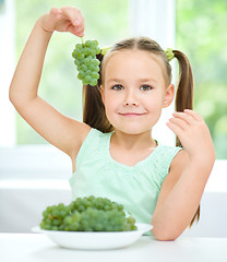 Image showing Cute little girl is eating green grapes