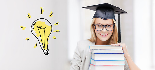 Image showing happy student woman in mortarboard with books