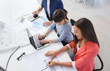 Image showing creative team with laptop and blueprint at office