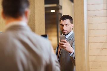 Image showing man in suit taking mirror selfie at clothing store