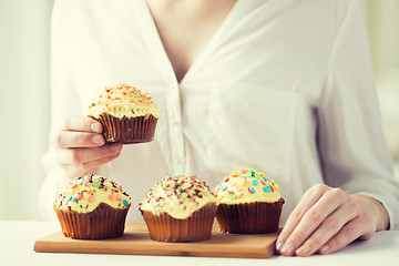 Image showing close up of woman with glazed cupcakes or muffins