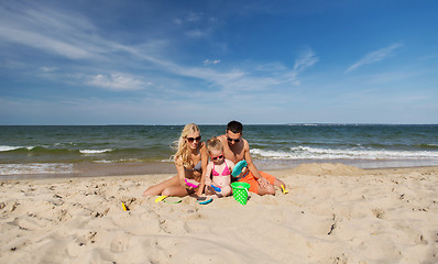 Image showing happy family playing with sand toys on beach