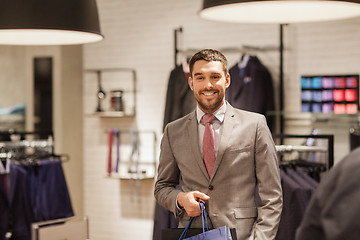 Image showing happy man with shopping bags at clothing store