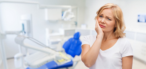 Image showing unhappy woman suffering toothache at dental office