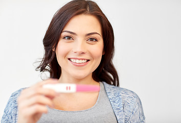 Image showing happy smiling woman holding home pregnancy test
