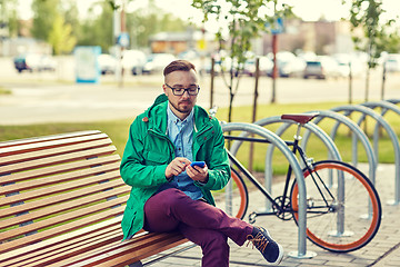 Image showing happy young hipster man with smartphone and bike