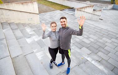 Image showing happy couple waving hands outdoors on city street