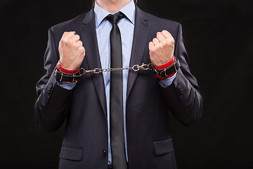 Image showing man in a business suit with leather bound with handcuffs. sex Toys