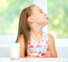 Image showing Sad little girl with a glass of milk