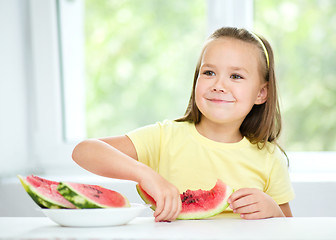 Image showing Cute little girl is eating watermelon