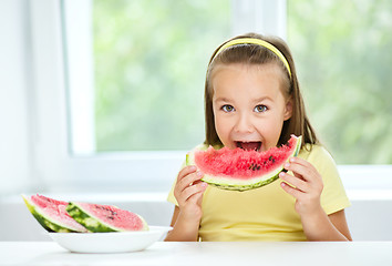 Image showing Cute little girl is eating watermelon