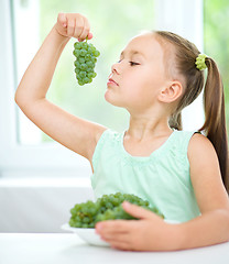 Image showing Cute little girl is eating green grapes