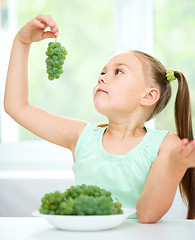 Image showing Cute little girl is eating green grapes